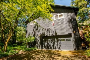A two-story house with a garage, surrounded by trees. - Riverfront 3-bedroom house in enchanting Mount Hood Village with private hot tub (Mount Hood Village)