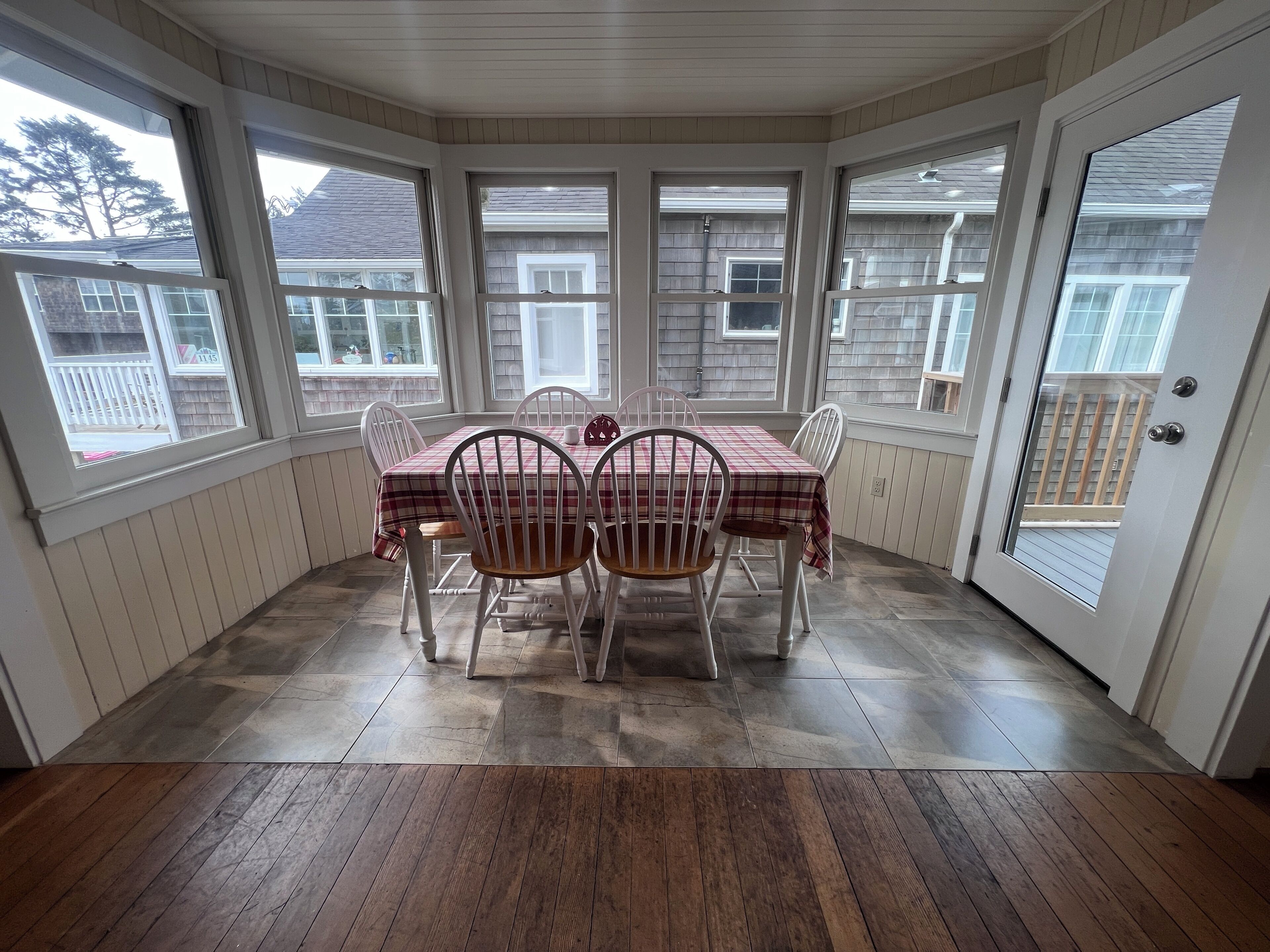 A dining area with a table and chairs, large windows, and a view of the outside.