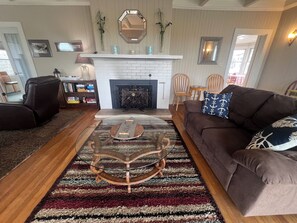 A living room with a fireplace, a sofa, a coffee table, and a bookshelf. - Wave Watcher - Oceanfront Home on the Promenade - Beach Access - Sleeps 10 Max (Seaside)
