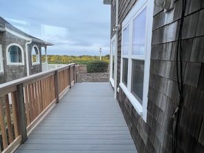 A wooden deck leading to a building with large windows and a white railing. - Wave Watcher - Oceanfront Home on the Promenade - Beach Access - Sleeps 10 Max (Seaside)