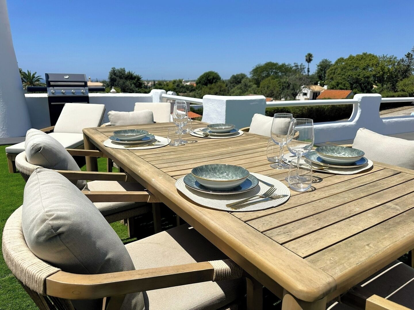 Un espace de restauration en plein air avec une table en bois prévue pour quatre personnes, entourée de chaises rembourrées.