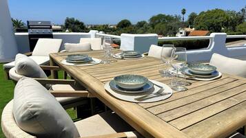 Un espace de restauration en plein air avec une table en bois prévue pour quatre personnes, entourée de chaises rembourrées.