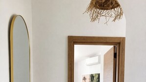 Ein Flur, der zu einem Raum mit Holztür, Spiegel und gewebtem Korb führt.