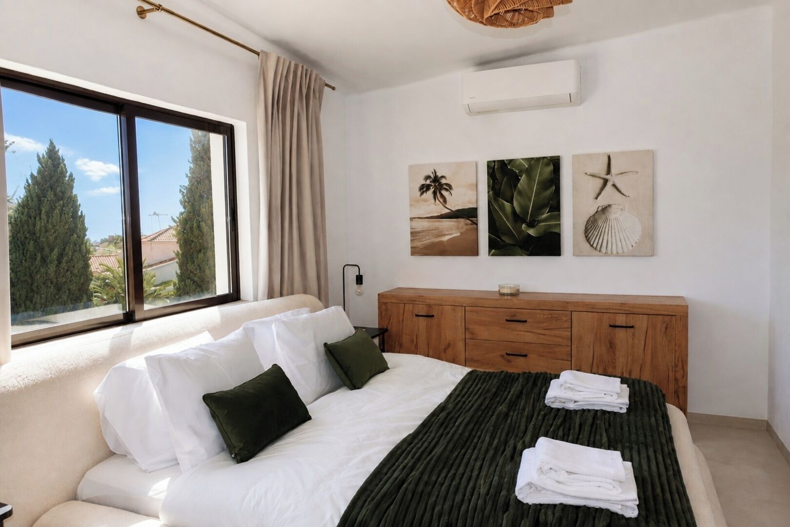 A bedroom with a bed, a wooden dresser, and a window with a view of trees.