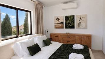 A bedroom with a bed, a wooden dresser, and a window with a view of trees.