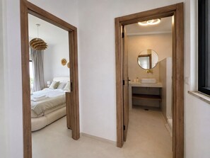A hotel room with a bed, a bedside table, a mirror, and a window. - Bright 2-BR Apt with Spacious Terrace and Sea Views (Carvoeiro)