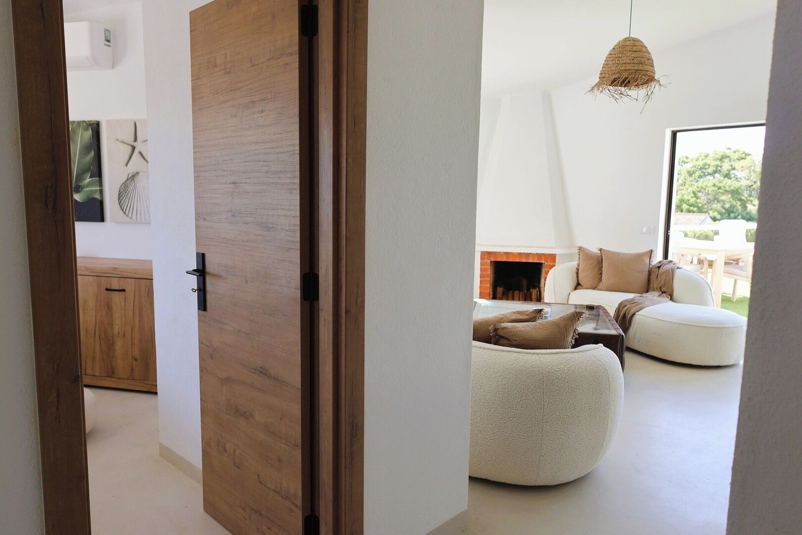 Un intérieur moderne avec une porte en bois, un canapé blanc et un luminaire suspendu.