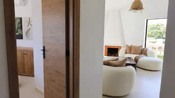 Un intérieur moderne avec une porte en bois, un canapé blanc et un luminaire suspendu.