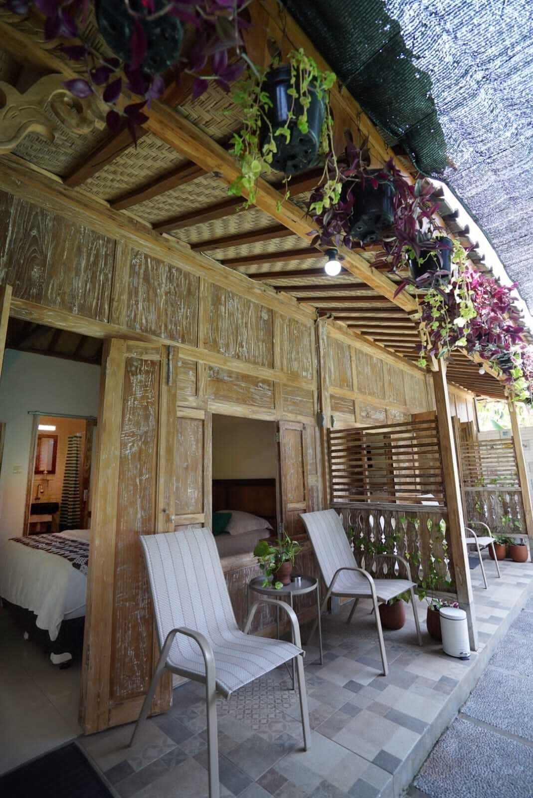 Un espacio de estar al aire libre cubierto, con sillas y plantas en macetas.