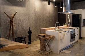 Une cuisine moderne dotée d’un îlot central, d’appareils électroménagers en acier inoxydable et d’un design minimaliste.