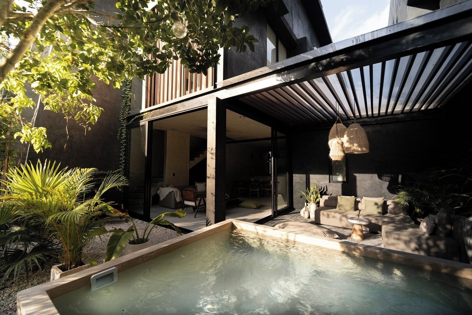A modern outdoor pool area with a minimalist design, surrounded by potted plants and a wooden deck.