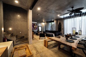 Un vaste espace de vie doté d’un haut plafond, une table à manger dressée avec de l’argenterie et un canapé moderne.