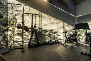 Ein Fitnessstudio mit Trainingsgeräten, darunter ein Squat-Rack, Kettlebells und ein Ergometer.