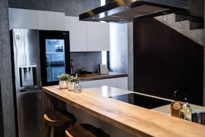 Eine moderne Küche mit einem Edelstahl-Kühlschrank, einem Wasserspender und einer Holzausziehtheke mit Barhocker.