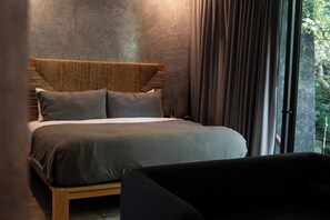 Une chambre à coucher moderne avec un grand lit, une tête de lit en bois et une vue sur la verdure par la fenêtre.