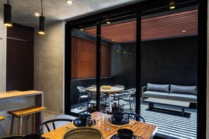 A modern dining area with a wooden table, black chairs, and a glass partition. - Casa Naya - 2 Pools, Near Beach, VIP Concierge (Tulum)