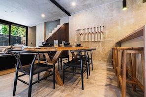 A modern dining area with a wooden table and chairs, a staircase, and a macrame wall hanging. - Casa Naya - 2 Pools, Near Beach, VIP Concierge (Tulum)