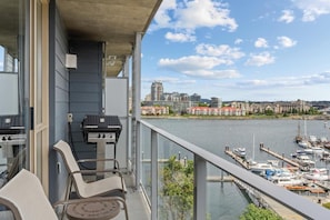 A balcony with a grill, chairs, and a view of a marina with boats and buildings across the water. - Peak July Escape! Spacious 2BR Suite in the Heart of Victoria (Victoria)