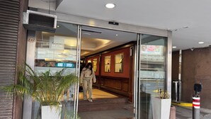 Entrada d'hotel amb portes de vidre, una planta en test i una escala que hi mena.