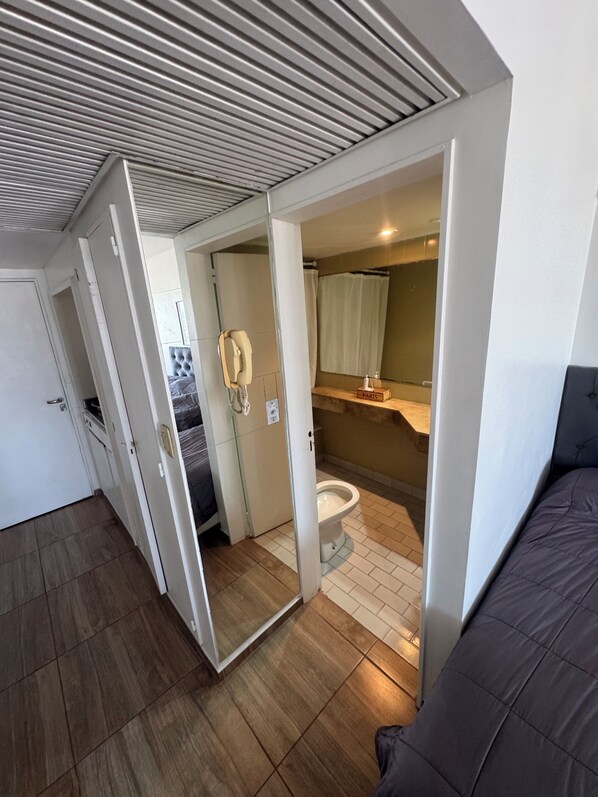 Une petite pièce comprenant des toilettes, une douche et un lit.