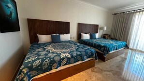 Habitación de hotel con dos camas, cada una con una colcha estampada y cabeceros de madera.