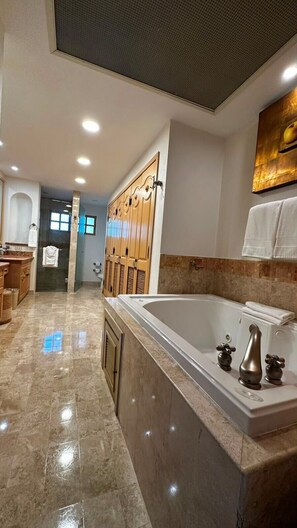 Um banheiro moderno com uma banheira grande, armários de madeira e piso de mármore.