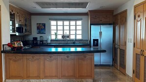 Una cocina con armarios de madera, una isla central, un refrigerador y un ventanal con vistas.