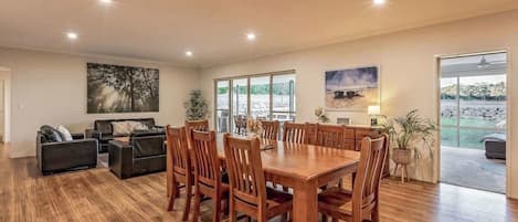 Amplia sala de estar con mesa de comedor de madera, asientos cómodos y ventanas grandes que ofrecen vistas al exterior.