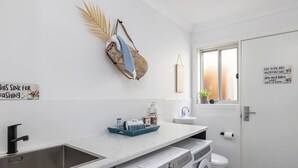 Casa de banho moderna com lavatório, sanita e máquina de lavar roupa. Tem uma janela com vista para o exterior.