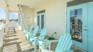 Une véranda couverte avec des fauteuils Adirondack bleu clair et une terrasse en bois.