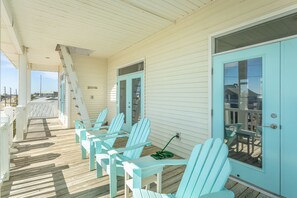 Eine überdachte Veranda mit hellblauen Adirondack-Stühlen und einer Holzterrasse.