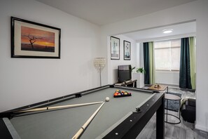A pool table with balls and cues, a television, and framed artwork on the wall. - 3 Bedroom House - Pool Table, Opp Train Station (Manchester)