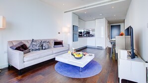 Ein modernes Wohnzimmer mit Sofa, Couchtisch und einer Küche im Hintergrund.