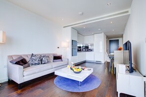 A modern living room with a sofa, coffee table, and a kitchen in the background. - Luxury City Apartment in Central London (London)