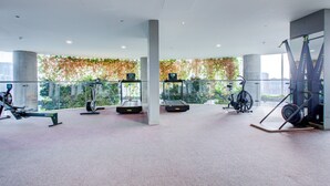 Ein modernes Fitnessstudio mit unterschiedlichen Trainingsgeräten, großen Fenstern und Blick auf Grünflächen.