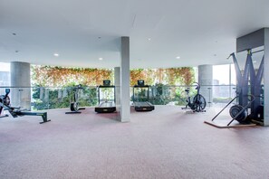 A modern gym with various exercise equipment, large windows, and a view of greenery outside. - Luxury City Apartment in Central London (London)