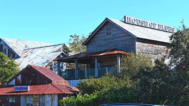 Um edifício rústico com uma placa que diz "HOUSE OF BLUES" e um prédio menor com a placa "GEAR SHOP".