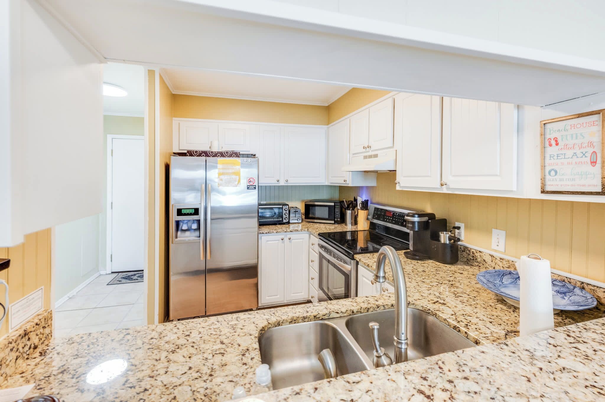 A modern kitchen with stainless steel appliances, a granite countertop, and white cabinetry.