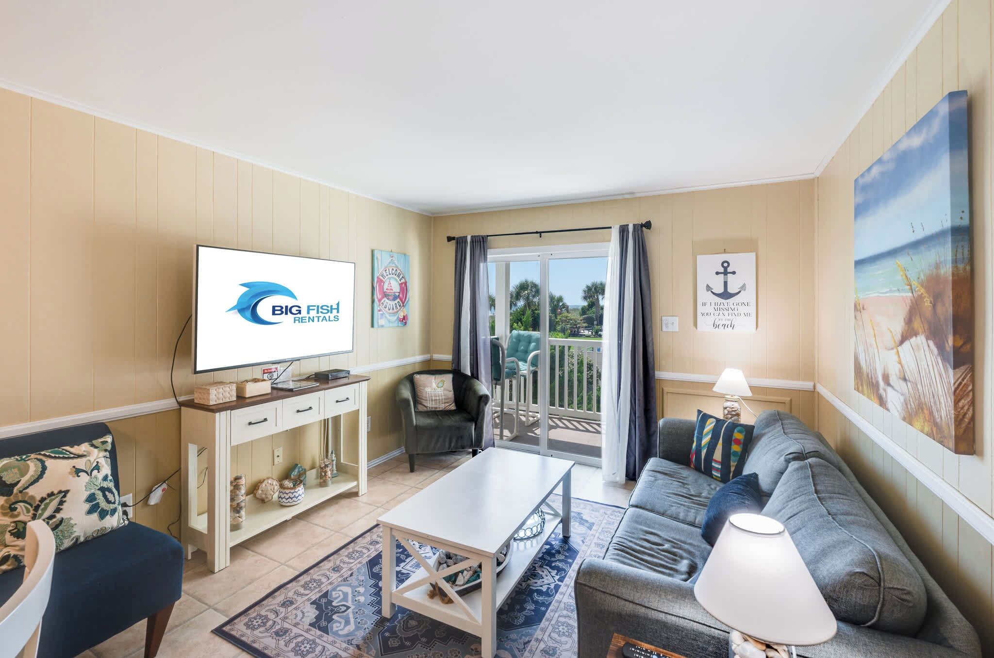 Ein Wohnzimmer mit Fernseher, einer Couch, einem Couchtisch und einem Balkon mit Blick.