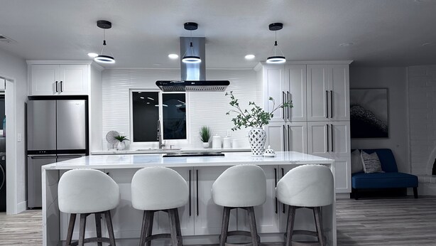 Una cocina moderna con una isla central, taburetes de bar y un horno empotrado.