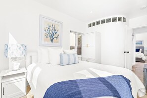 Ein modernes Schlafzimmer mit einem großen Bett, einem Nachttisch, einem Kleiderschrank und einem Fenster.