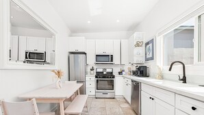 Una cocina moderna con armarios blancos, horno empotrado, microondas y pileta.
