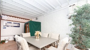 Un comedor con una mesa, sillas, una planta en maceta y un cuadro de empalme eléctrico en la pared.