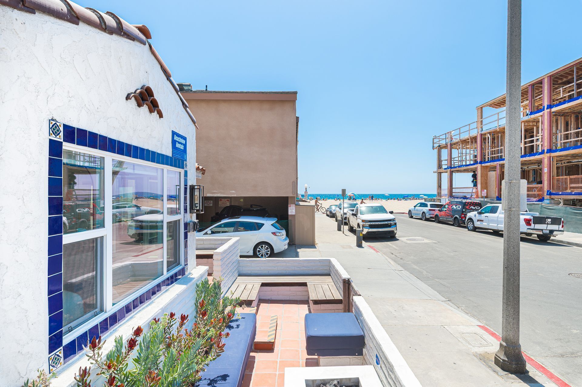 Ein strandnahes Anwesen mit Parkplatz, einem Gebäude mit Kachelfassade und Blick auf den Strand.