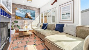 Una sala de estar con un sofá, una mesa de centro y un cuadro de una playa.