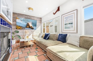 Ein Wohnzimmer mit einer Couch, einem Couchtisch und einem Bild von einer Strandlandschaft.