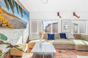 Ein Wohnzimmer mit großem Fenster, einer Couch, einem Couchtisch und einer Wandgestaltung.