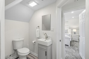 Een badkamer met toilet, wastafel en spiegel.
