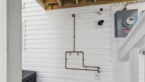 Un cuarto de servicio con paredes de revestimiento blanco, techo de madera y un panel eléctrico gris.
