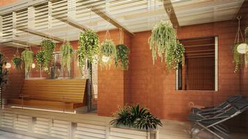 A modern outdoor seating area with a wooden bench and lounge chairs, surrounded by hanging plants and a ceiling with linear light fixtures.